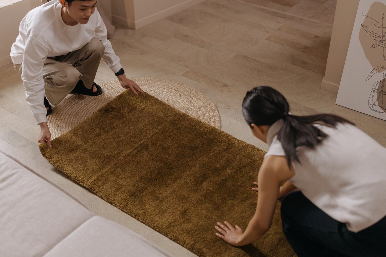 A Couple Laying Down a Brown Rug on the Floor